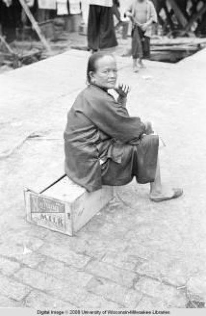 Hong Kong, woman sitting on a crate at a pier
