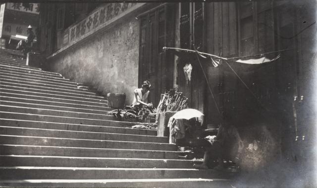 An umbrella repairer working beside a street