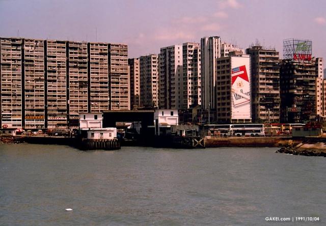 1991 HK harbor: Ferry Point Estate high-rises behind a vehicular ferry pier and Marlboro billboard.