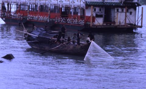 A cast net fishing boat and a floating restaurant in Kowloon(?) Bay.