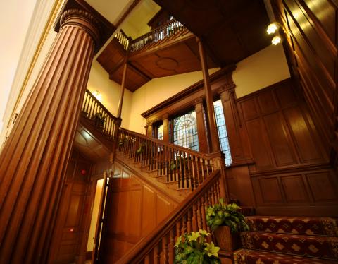 Grand wooden staircase and stained-glass window at the main hall
