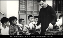 Father Enea Tapella hands out food to children