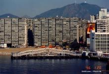 1996 HK harbor: Ferry Point Estate blocks behind a floating pier bridge, with mountains in back.