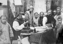 Chinese craftsman with a group of young spectators, ca. 1910