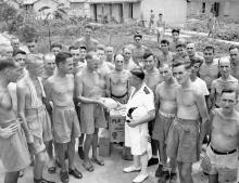 Cmdr. Peter MacRitchie of HMCS Prince Robert with liberated Canadian prisoners of war at Sham Shui Po Camp, Hong Kong 