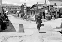 Woman walking through Shau Tau Kok village past border marker
