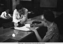Hong Kong, American evacuee writing a travelers cheque during World War II