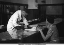 Hong Kong, an American evacuee writing a travelers cheque at the American Express Travel Department during World War II